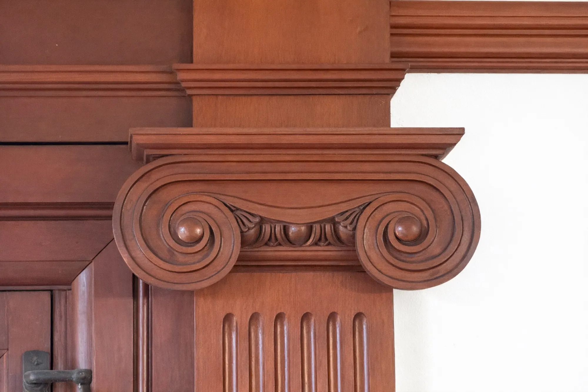 A hand-carved cedar Ionic capital atop a fluted pilaster